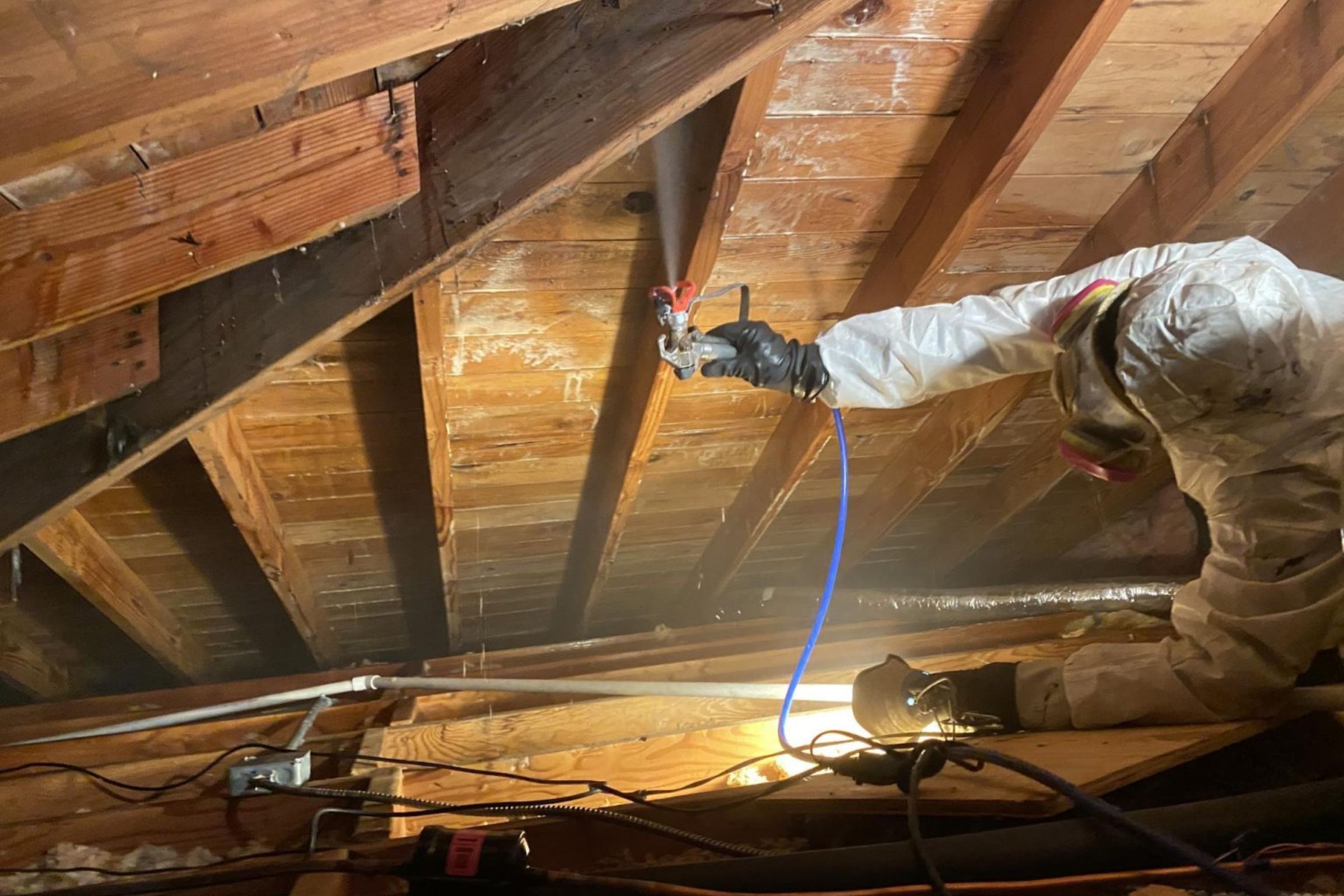 A man wearing a white jacket and safety gear works on a roof, focusing on mold removal in Joliet, IL.