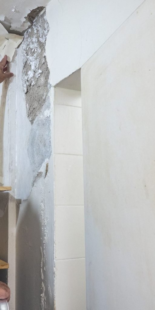 A man applies white paint to a wall, illustrating a mold removal service in Joliet, IL.